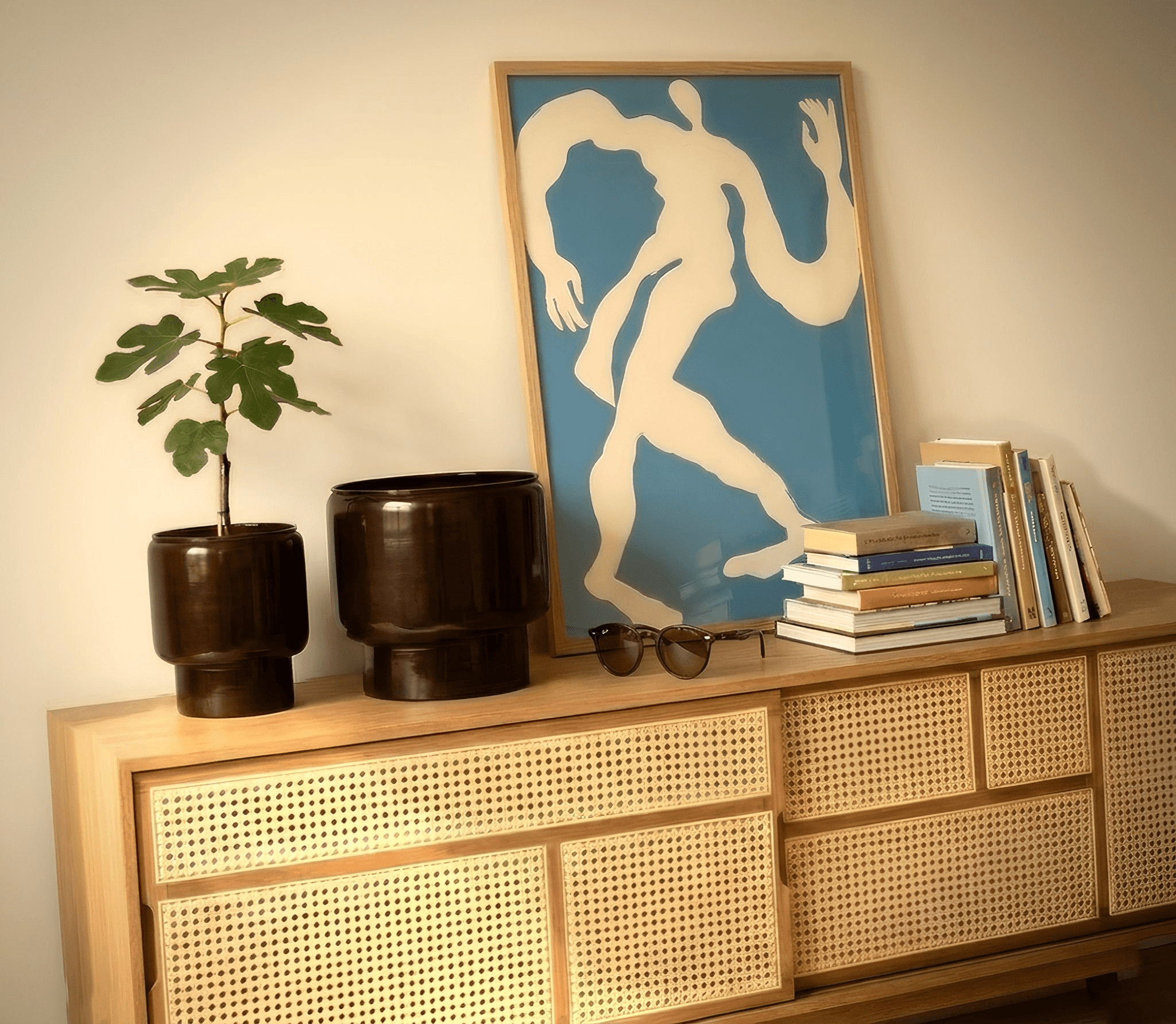 Dancer print resting on a cane sideboard with books and a fig plant